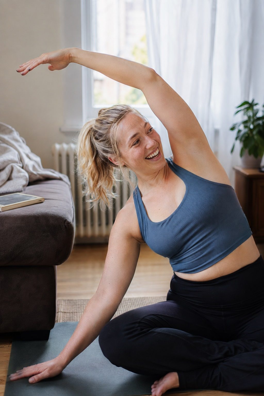 A woman smiling mid side-stretch on a mat in her living room